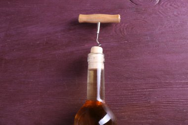 Tirbuşon ve mor ahşap arka plan üzerinde şarap şişesi