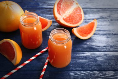 Greyfurt suyu şişeleri ve koyu mavi ahşap zemin üzerine taze meyve