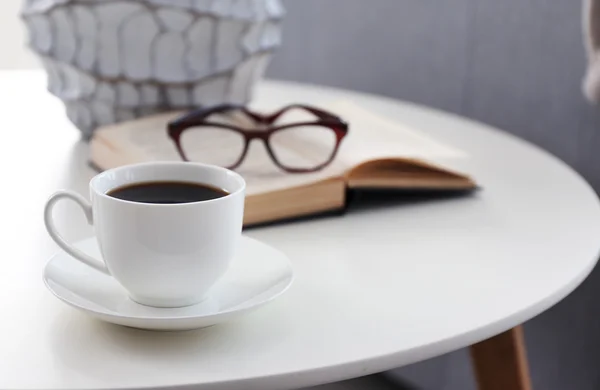 Cup of coffee with book on table in room — Stock Photo, Image