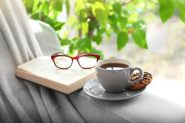 Cup of coffee with book on sofa in room — Stock Photo, Image