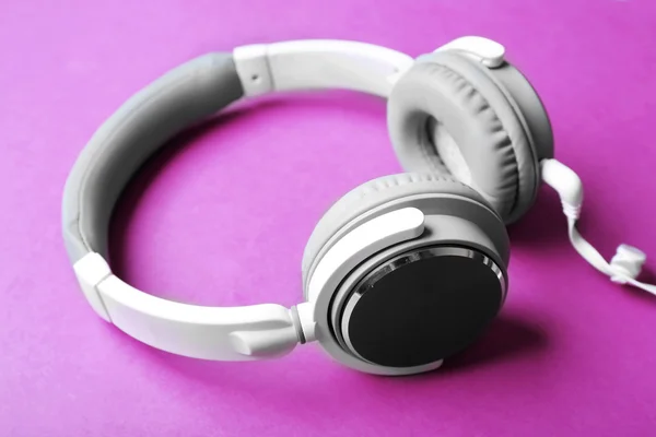 Bílé a šedé sluchátka na fialovém pozadí — Stock fotografie