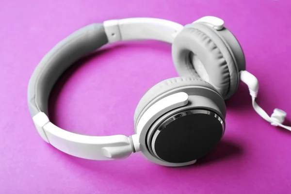 Auriculares blancos y grises sobre fondo morado — Foto de Stock