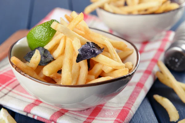 Pommes frittierte Kartoffeln in Schüssel mit Basilikum und Soße auf altem Holzgrund — Stockfoto