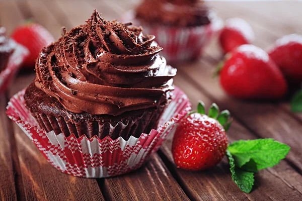 Chocolade cupcakes en aardbeien op houten achtergrond — Stockfoto