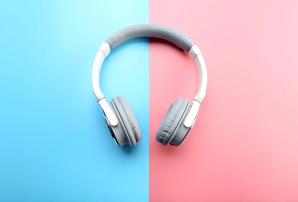 Wireless white and grey headphones on pink-blue background