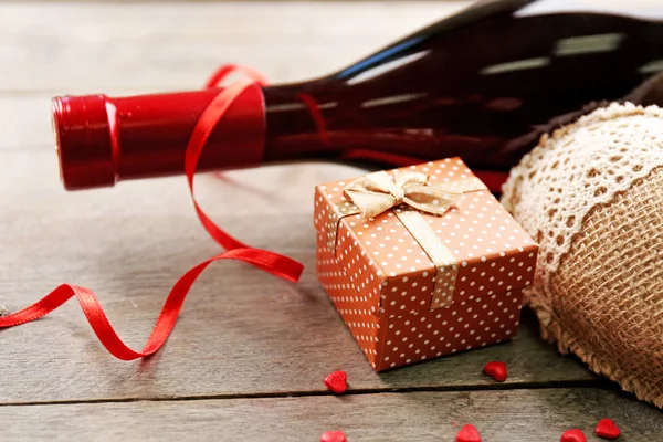 Установка бутылки вина, подарок в коробке и другие украшения, на деревянном фоне — стоковое фото