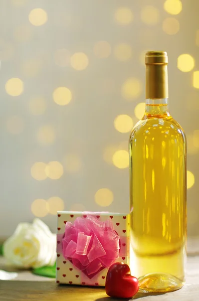 Configuração de uma garrafa de vinho, um presente na caixa e outra decoração, sobre fundo borrado — Fotografia de Stock