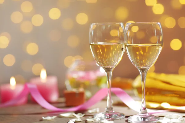 Glasses of wine, white roses and candles, on blurred background — Stock Photo, Image