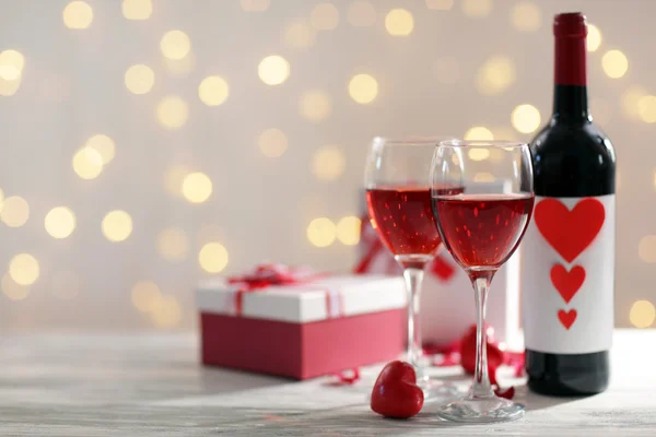 Einstellung von Gläsern mit Wein, Flasche und einem Geschenk in der Schachtel, auf weißem unscharfem Hintergrund — Stockfoto