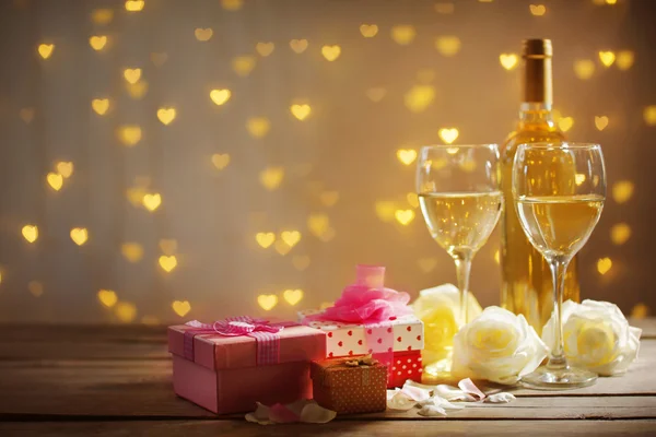 Bicchieri di vino, rose bianche un regalo nella scatola e una bottiglia, su sfondo sfocato — Foto Stock