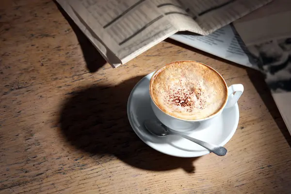 Csésze finom cappuccino és a napilapok, a táblázatban — Stock Fotó