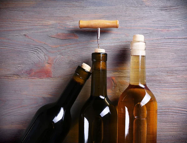 Drei Flaschen Wein und Korkenzieher auf Holzgrund — Stockfoto