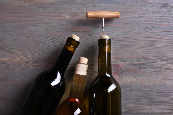 Tres botellas de vino y sacacorchos sobre fondo de madera —  Fotos de Stock