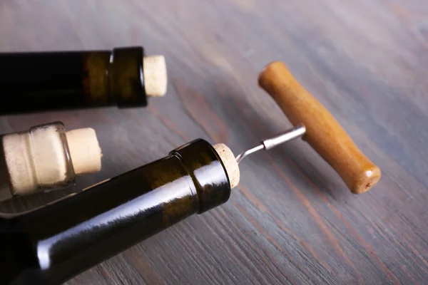 Tres botellas de vino y sacacorchos sobre fondo de madera —  Fotos de Stock