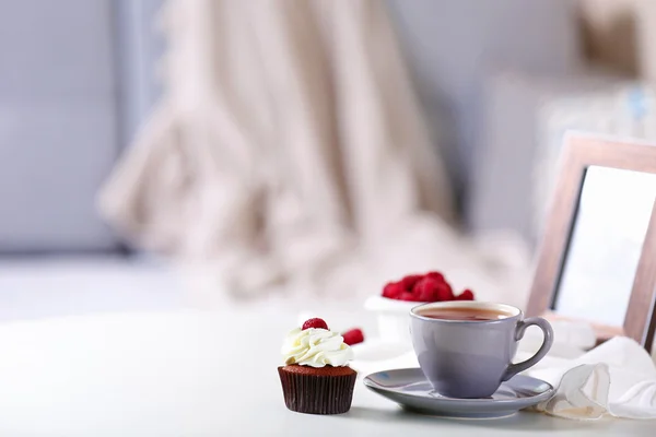 Beautiful chocolate cupcake with raspberry and cup of tea, on table — Stock Photo, Image