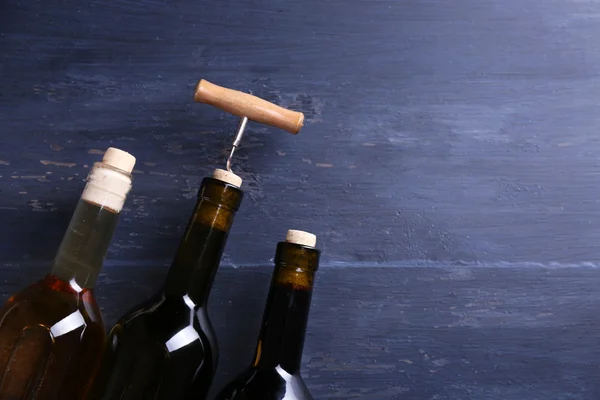 Üç şişe şarap ve tirbuşon mavi ahşap zemin üzerine — Stok fotoğraf