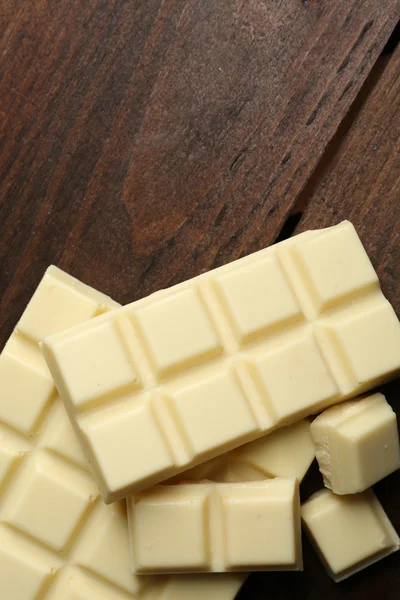 Piezas de chocolate blanco sobre fondo de madera — Foto de Stock