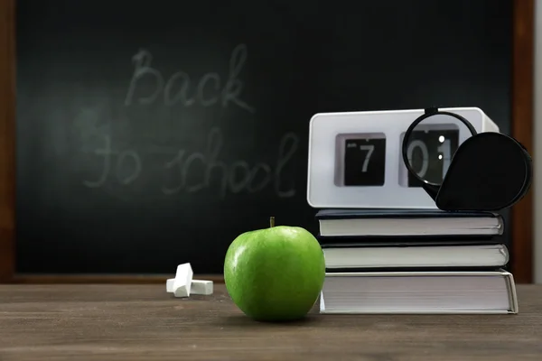 Apple, books, clock and magnifier on desk background