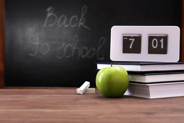 Apple, books and clock on desk background — Stock Photo, Image