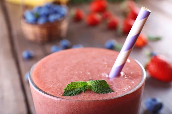 Um copo de smoothie fresco frio com bagas e hortelã, em fundo de madeira, close-up — Fotografia de Stock