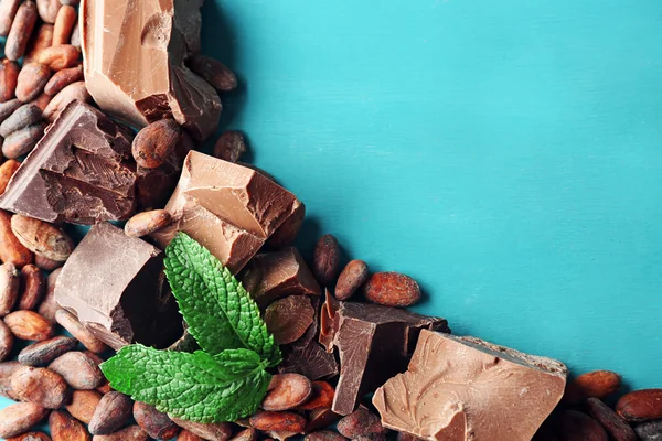 Gelap dan susu coklat potongan dan biji kakao pada warna latar belakang kayu — Stok Foto
