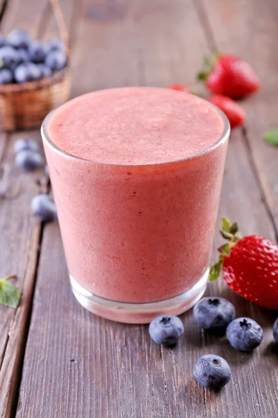 Um copo de smoothie frio fresco com bagas, em fundo de madeira — Fotografia de Stock