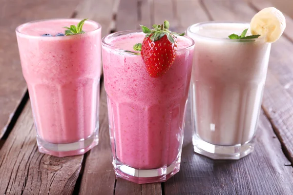 Vasos de batido frío fresco con frutas y bayas, sobre fondo de madera —  Fotos de Stock