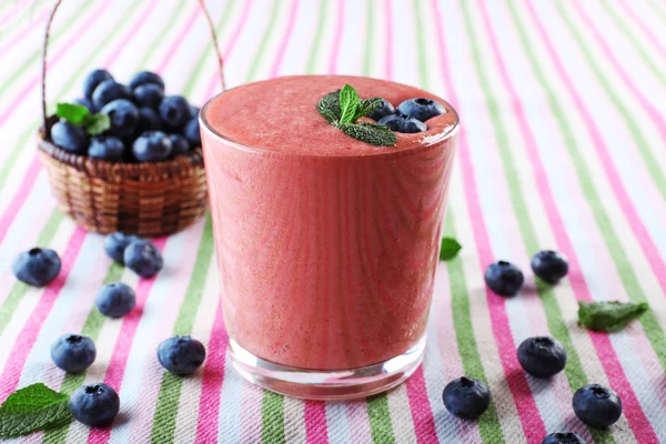 Um copo de smoothie frio fresco com bagas, em fundo de toalha de mesa forrada — Fotografia de Stock