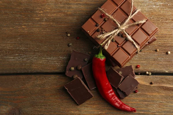 Zwarte chocolade stukken met peper op houten achtergrond — Stockfoto
