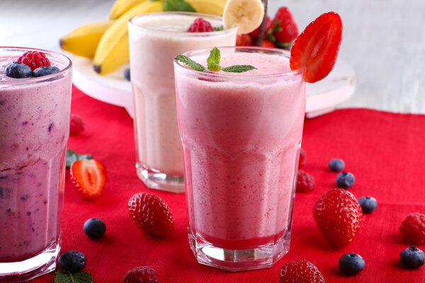 Milkshakes with berries at red textile on light background