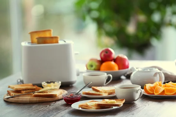 Mesa servida para el desayuno con tostadas, café y fruta, sobre fondo borroso — Foto de Stock