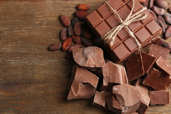 Trozos de chocolate, virutas y granos de cacao sobre fondo de madera de color —  Fotos de Stock