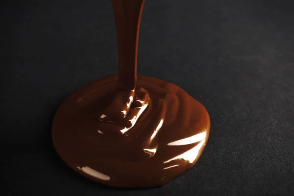 Coklat dituangkan di permukaan gelap — Stok Foto