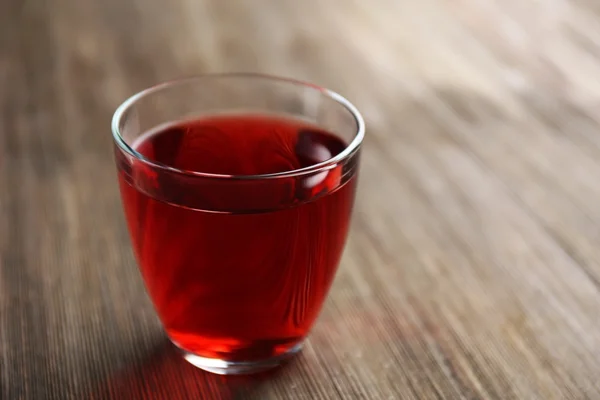 Um copo de suco de granada saboroso, em fundo de madeira — Fotografia de Stock