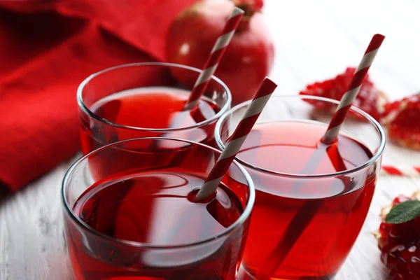 Three glasses of tasty juice and garnet fruit on the table, close-up — Stock Photo, Image