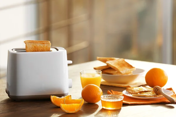 Mesa servida para café da manhã com torrada e suco de laranja, em fundo embaçado — Fotografia de Stock