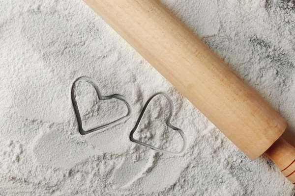 Hearts of flour and rolling pin on gray background — Stock Photo, Image