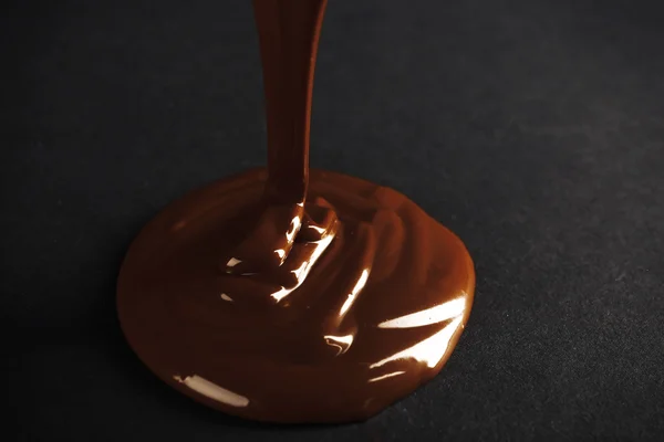 Chocolate poured on dark surface — Stock Photo, Image