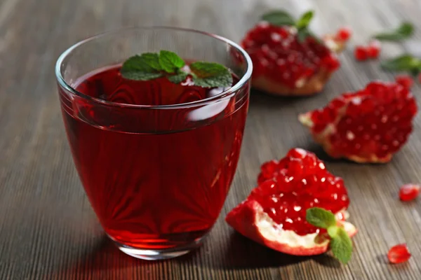 Un verre de jus savoureux et de fruits grenat, sur fond de bois — Photo