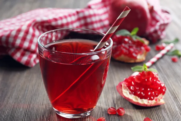 Bir bardak lezzetli suyu ve garnet meyve, ahşap arka plan, yakın çekim — Stok fotoğraf