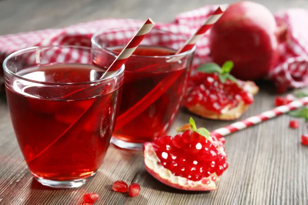 Two glasses of tasty juice and garnet fruit, on wooden background — Stock Photo, Image