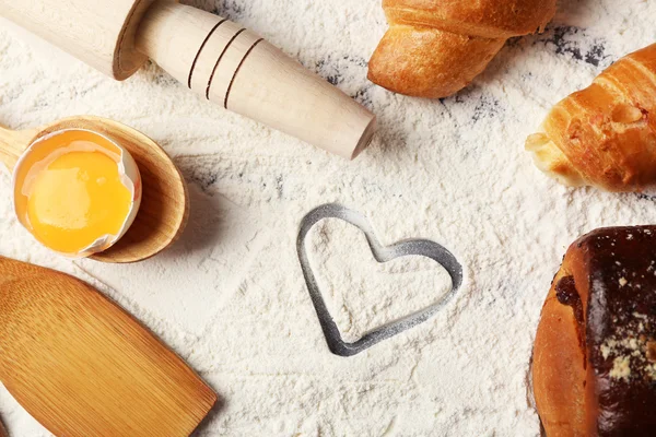 Corazón de harina, croissant y utensilios de cocina de madera sobre fondo gris —  Fotos de Stock