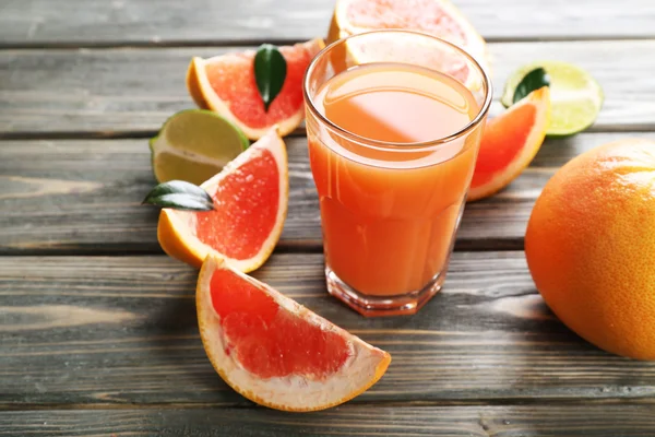 Glas van grapefruitsap en vers fruit op houten achtergrond — Stockfoto