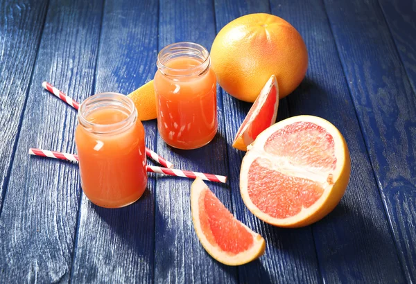 Greyfurt suyu şişeleri ve koyu mavi ahşap zemin üzerine taze meyve