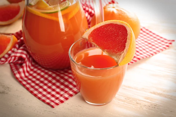 Jar of citrus juice and fresh fruits on light wooden background — Stock Photo, Image