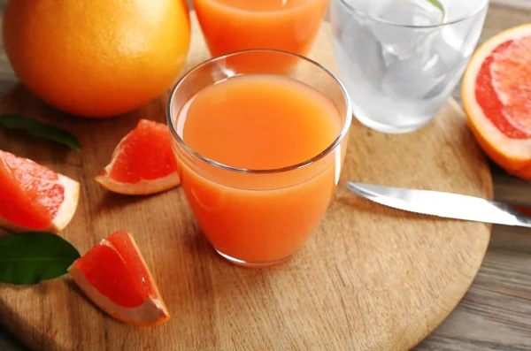 Jus d'agrumes avec glace et fruits frais sur planche à découper — Photo