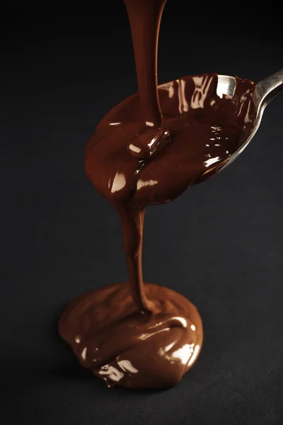 Chocolate poured on a spoon on dark background — Stock Photo, Image