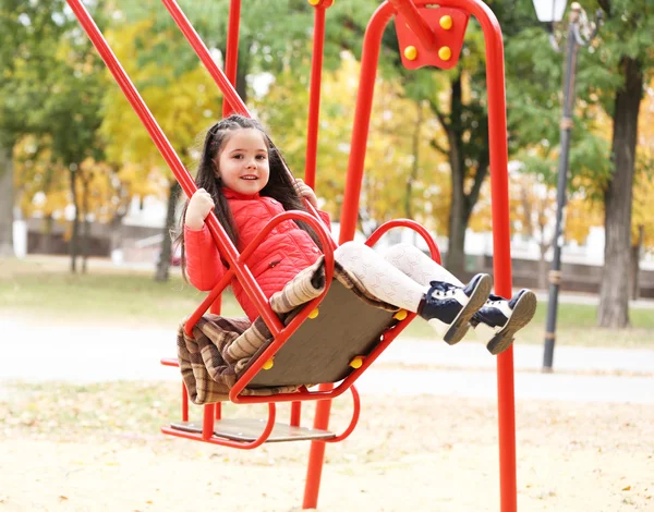 Маленька дівчинка на гойдалці в міському парку — стокове фото