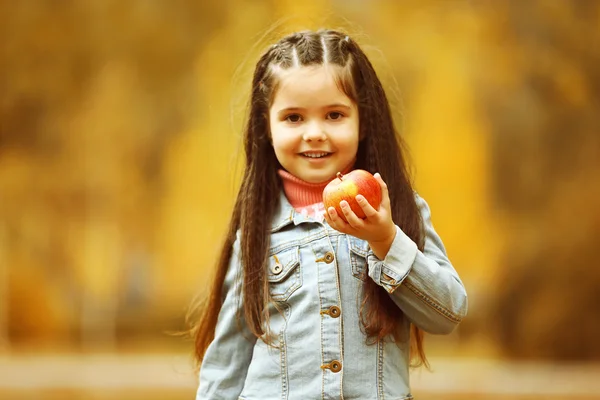 Красивая маленькая девочка держит яблоко — стоковое фото