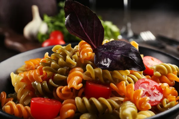 Läckra makaroner maträtt i svart skål på serveras träbord — Stockfoto